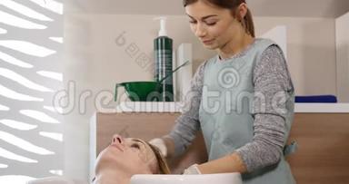 现代水疗中心的头发护理。 在发廊的理发师洗头发的女人。 女人在水疗中心洗头。 水疗中心